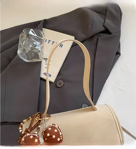 Detail of off-white leather tote bag handle with brown polka dot bow on a gray blazer