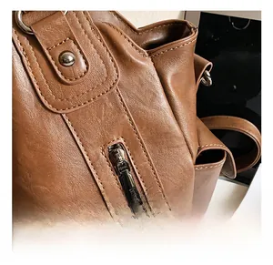 Close-up of caramel brown leather tote bag with premium metal zippers and rivet details