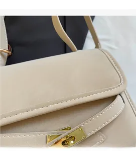 Detail of beige grainy leather shoulder bag featuring white contrast stitching and gold lock
