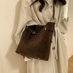 Close-up of deep brown suede bucket bag with gold hardware and protective metal feet