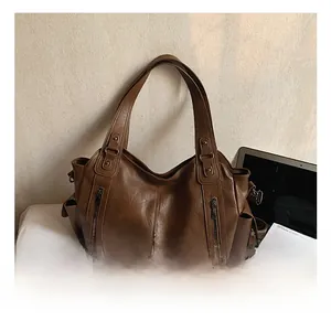 Detail view of large brown tote bag with metal zipper pockets and textured faux leather