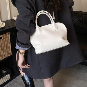 Detail of off-white leather shell bag showing double handles and smooth texture