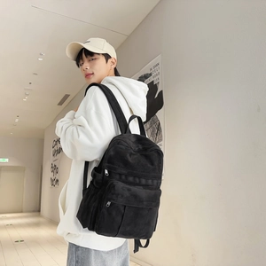 Urban lifestyle shot of a black canvas backpack worn by a student in a bright corridor