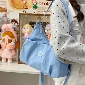 Détail du sac cabas plissé bleu clair avec badge logo rond et fermeture à glissière