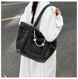 Detail of grey washed denim tote bag featuring decorative pearl and silver butterfly chain