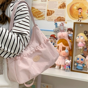 Détail du sac cabas plissé rose avec cordon latéral et écusson logo ovale sur le devant