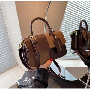 Detailed shot of two-tone brown leather and suede stitching on minimalist handbag