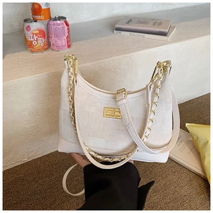 Detail of beige plaid dumpling bag with golden twist lock and chain shoulder strap