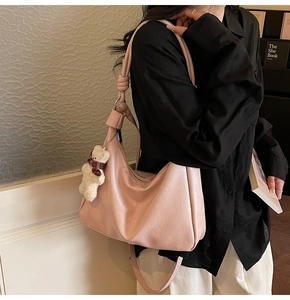 Detail of pink PU leather tote bag featuring a knot handle and a cute plush bear charm