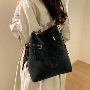 Detail of black bucket bag with gold hardware and a stylish leopard print silk scarf