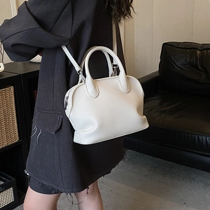 Close-up of off-white litchi grain leather texture on a stylish Boston shell handbag