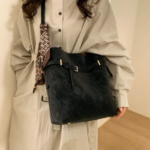 Detailed view of a dark grey suede tote bag with decorative scarf and gold hardware