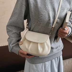 Detail view of cream pleated crossbody bag with gold hardware and embossed lettering
