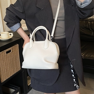Detailed view of beige shell handbag with lychee pattern leather and silver hardware