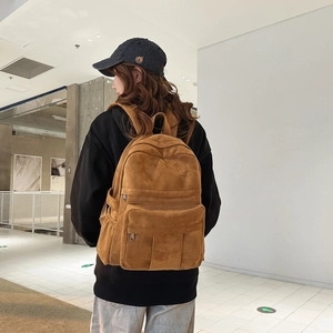 Detailed side view of a brown corduroy backpack with multi-pocket design on model