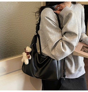 Black synthetic leather hobo bag featuring decorative stitching and a cute bear charm