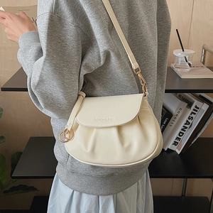 Detail view of cream white pleated PU leather handbag with gold ring charm and strap