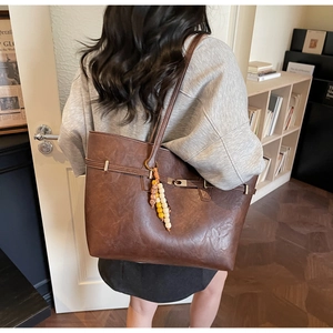 Detail of vintage brown tote bag with colorful beaded charm and metallic magnetic clasp