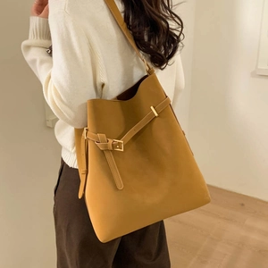 Brown leather bucket bag detail with adjustable strap and gold buckle on a model