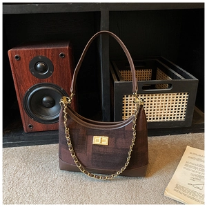 Close-up of vintage brown hobo bag featuring gold chain and metallic twist lock closure
