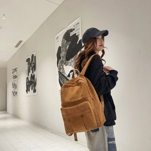 Side view of brown faux suede backpack with multi-pocket design in urban street setting