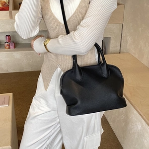Close-up of black lychee grain leather shell bag with meticulous stitching details