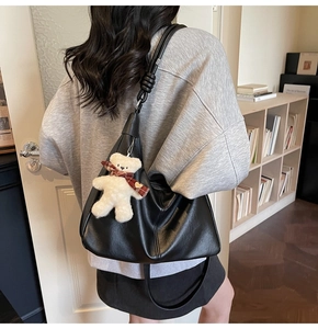 Detail of matte black hobo tote with knot shoulder strap and cute teddy bear charm