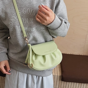 Detail of mint green saddle bag featuring pleated PU leather and gold metal hardware