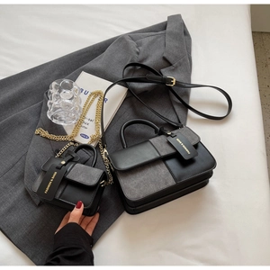 Detail of minimalist black and grey patchwork handbags with leather and chain straps