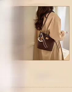 Macro detail of dark brown suede bucket bag featuring a wooden horse charm and gold hardware