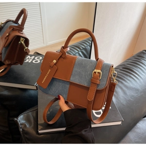 Detail of color-block bag with brown leather and blue denim material mix and gold hardware