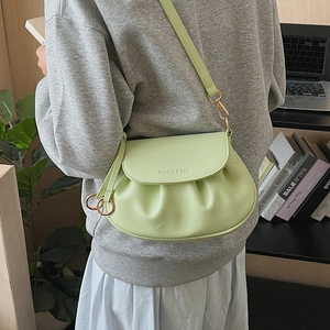 Detail of mint green pleated crossbody bag with gold buckle and fashion logo on the flap
