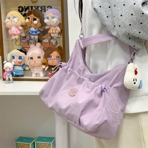 Détail du sac hobo en nylon violet avec plis à cordon et porte-clés ours blanc