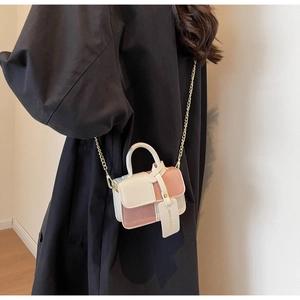 Detail of contrast color mini crossbody bag with metal chain strap on black coat
