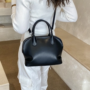 Minimalist black shell handbag detail showing smooth leather texture and crossbody strap