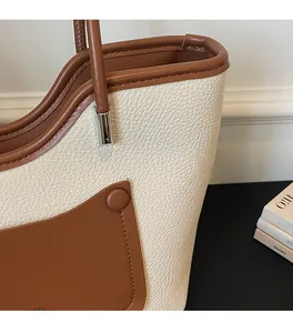 Dettaglio della trama in finta pelle martellata e della tasca marrone della borsa tote