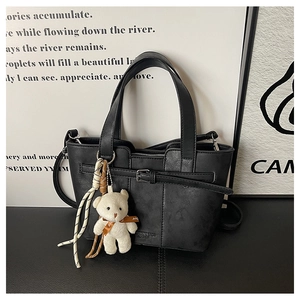 Detail der schwarzen Leder-Beuteltasche mit Plüschbär-Anhänger und Web-Quasten-Dekor