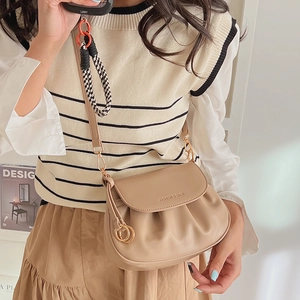 Detailed close-up of the pleated flap and gold metal hardware on the khaki shoulder bag
