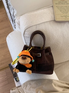 Dunkelbraune Vintage-Eimertasche mit niedlichem Hundeanhänger auf Stoffhintergrund