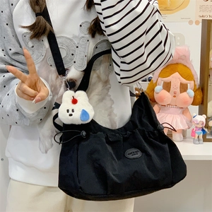 Détail du sac à main noir en toile avec cordon latéral et porte-clés lapin