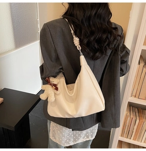 Detail of cream PU leather shoulder bag with knotted strap and cute plush bear charm