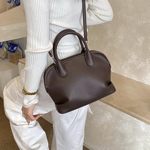 Detailed close-up of dark brown lychee pattern leather and metal hardware on the shell bag