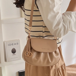 Detail of beige pleated crossbody bag with adjustable strap and golden ring charm