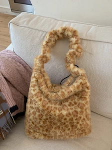 Plush leopard print tote bag with soft faux fur texture on a cozy home sofa