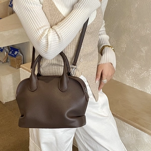 Detailed view of dark brown pebbled leather shell bag with silver hardware and shoulder strap