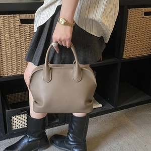 Detail of taupe litchi texture on a large capacity shell shaped leather handbag