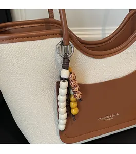 Dettaglio borsa tote in pelle con grana litchi, ciondolo di perle e logo frontale