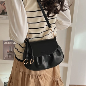 Detailed close-up of a pleated black faux leather bag with elegant gold hardware and strap