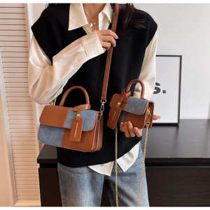 Detail of two-piece brown leather and blue denim patchwork handbag set with chain strap