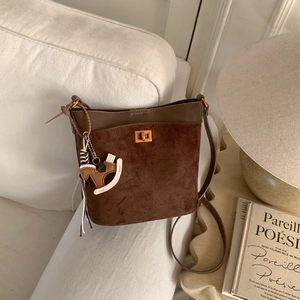 Detailed view of vintage patchwork bucket bag with suede texture and gold buckle on sofa